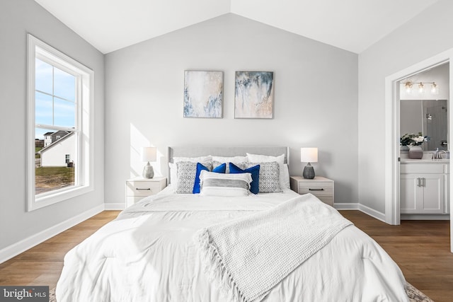 bedroom featuring sink, hardwood / wood-style floors, ensuite bathroom, and vaulted ceiling