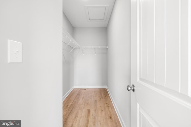 spacious closet with attic access and light wood-style flooring