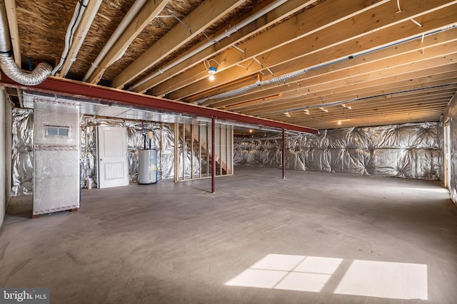 unfinished basement featuring visible vents and electric water heater