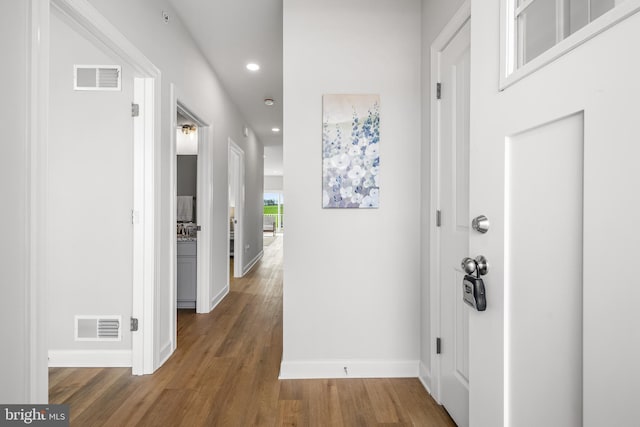 corridor featuring recessed lighting, visible vents, baseboards, and wood finished floors