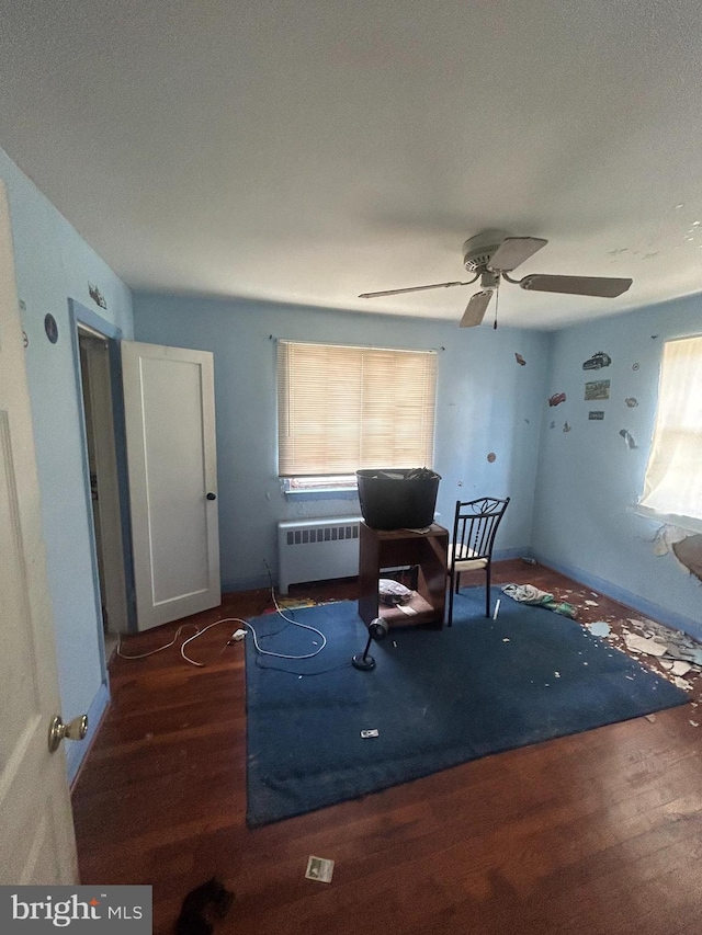 sitting room featuring dark hardwood / wood-style flooring, ceiling fan, radiator heating unit, and a healthy amount of sunlight