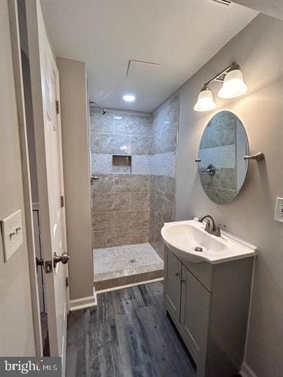 bathroom featuring a tile shower, wood-type flooring, and vanity