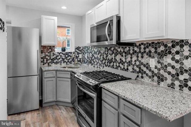 kitchen featuring light hardwood / wood-style floors, sink, white cabinetry, stainless steel appliances, and backsplash