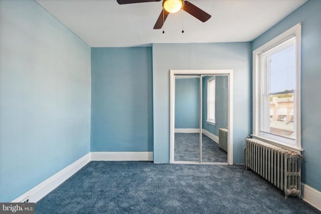 unfurnished bedroom with radiator heating unit, baseboards, a closet, and carpet flooring