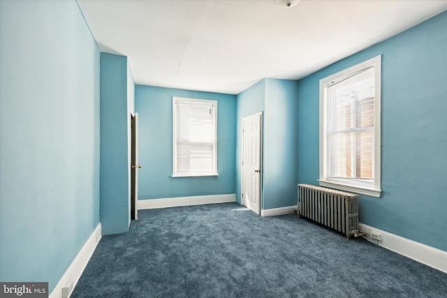 unfurnished bedroom featuring baseboards, dark colored carpet, and radiator