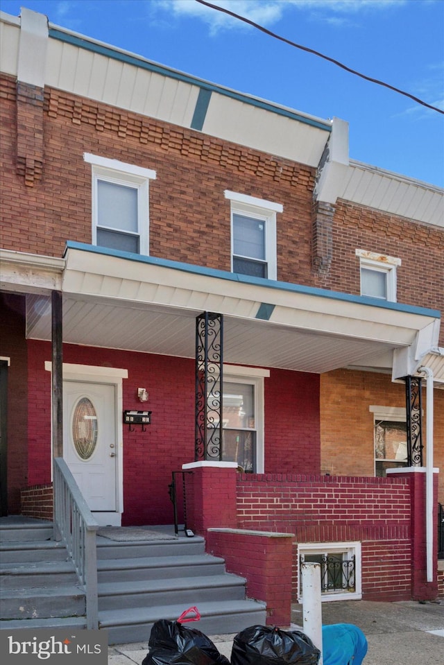 multi unit property featuring a porch and brick siding