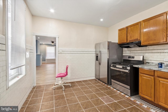 kitchen with brown cabinets, dark tile patterned floors, recessed lighting, appliances with stainless steel finishes, and under cabinet range hood