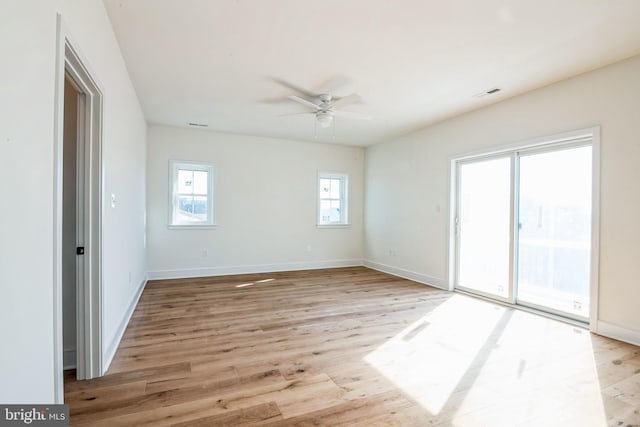 empty room featuring a ceiling fan, visible vents, light wood-style flooring, and baseboards