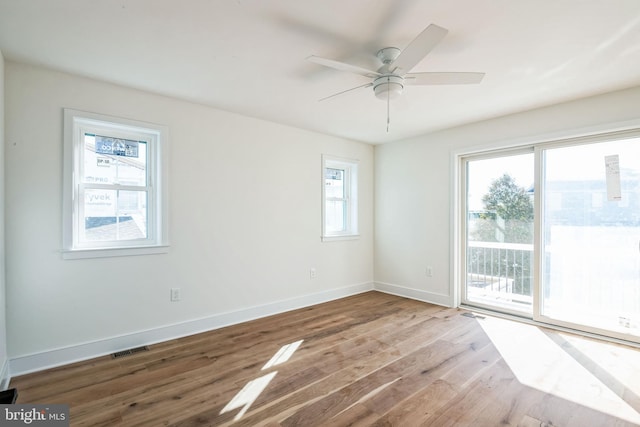 unfurnished room featuring a ceiling fan, baseboards, visible vents, and wood finished floors