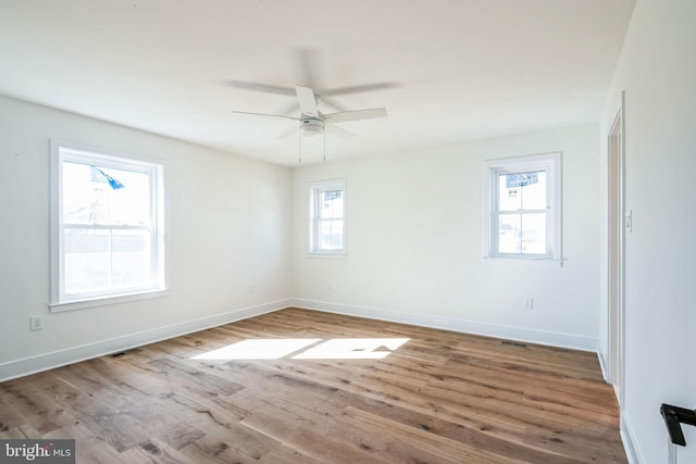 unfurnished room with ceiling fan, light wood-type flooring, visible vents, and baseboards