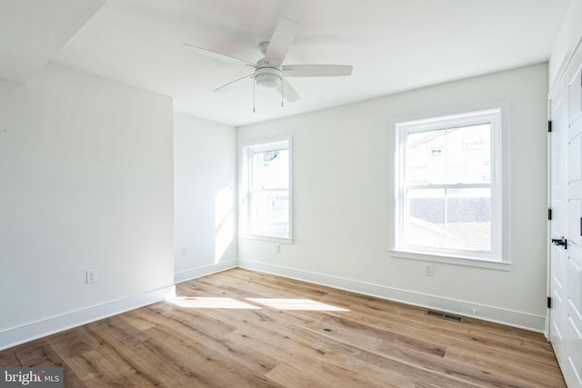 spare room featuring light wood finished floors, ceiling fan, visible vents, and baseboards