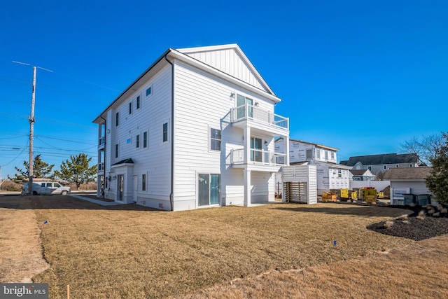 exterior space with a balcony, a lawn, and board and batten siding