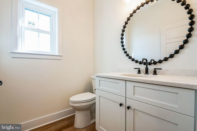 bathroom with toilet, baseboards, wood finished floors, and vanity