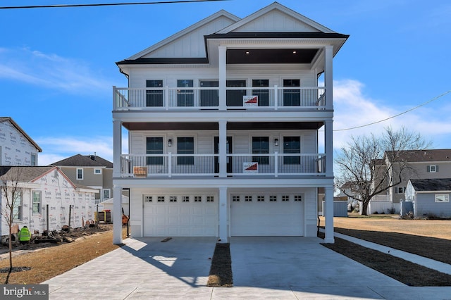 raised beach house with a garage, a balcony, board and batten siding, and concrete driveway