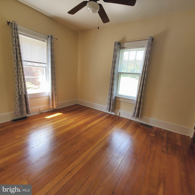 unfurnished room with visible vents, baseboards, and wood finished floors