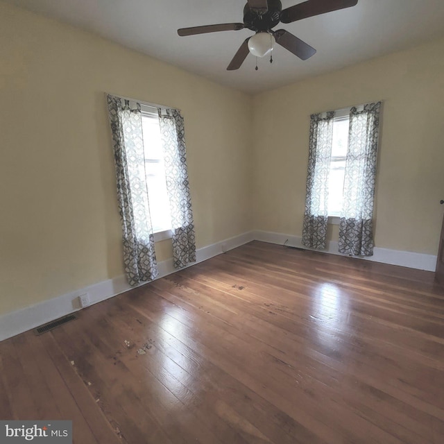 spare room featuring visible vents, dark wood-style flooring, and a wealth of natural light