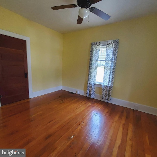 spare room featuring a ceiling fan, baseboards, and wood finished floors