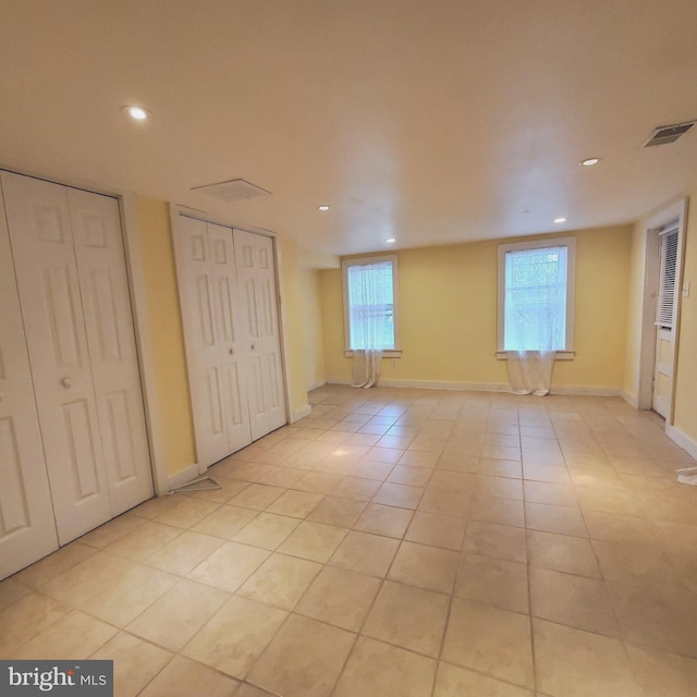 interior space featuring light tile patterned floors, recessed lighting, visible vents, baseboards, and multiple closets