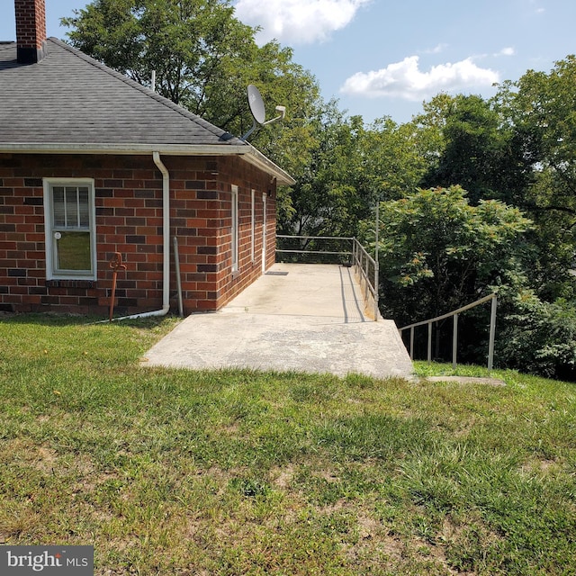 exterior space featuring brick siding, roof with shingles, and a lawn