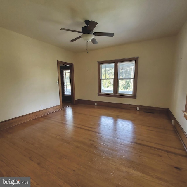 empty room with a ceiling fan, baseboards, and wood finished floors