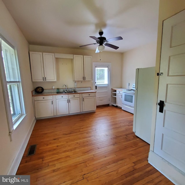 kitchen featuring white appliances, visible vents, white cabinetry, and a sink