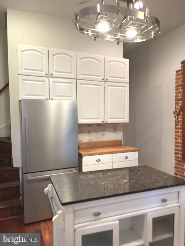 kitchen featuring freestanding refrigerator, dark wood-style flooring, white cabinetry, and dark stone countertops