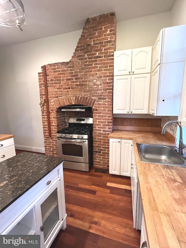 kitchen with white cabinets, dark wood finished floors, gas range, wood counters, and a sink