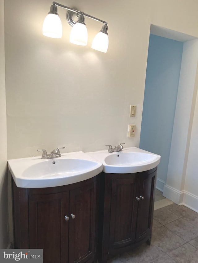 bathroom featuring tile patterned flooring, two vanities, a sink, and baseboards