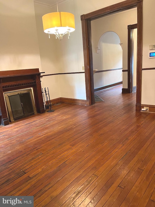 unfurnished living room featuring a glass covered fireplace, dark wood finished floors, and baseboards