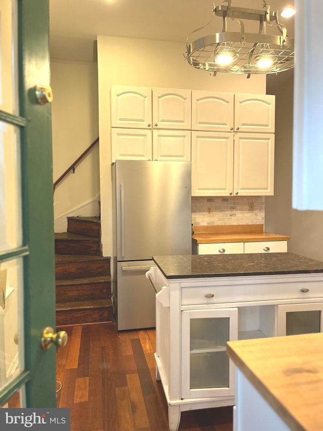 kitchen featuring dark wood finished floors, butcher block countertops, freestanding refrigerator, white cabinetry, and backsplash