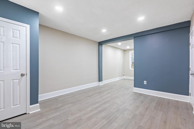 unfurnished room featuring a textured ceiling and light hardwood / wood-style floors