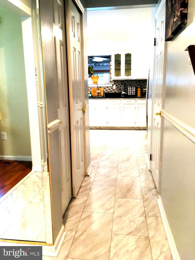 corridor with marble finish floor and baseboards