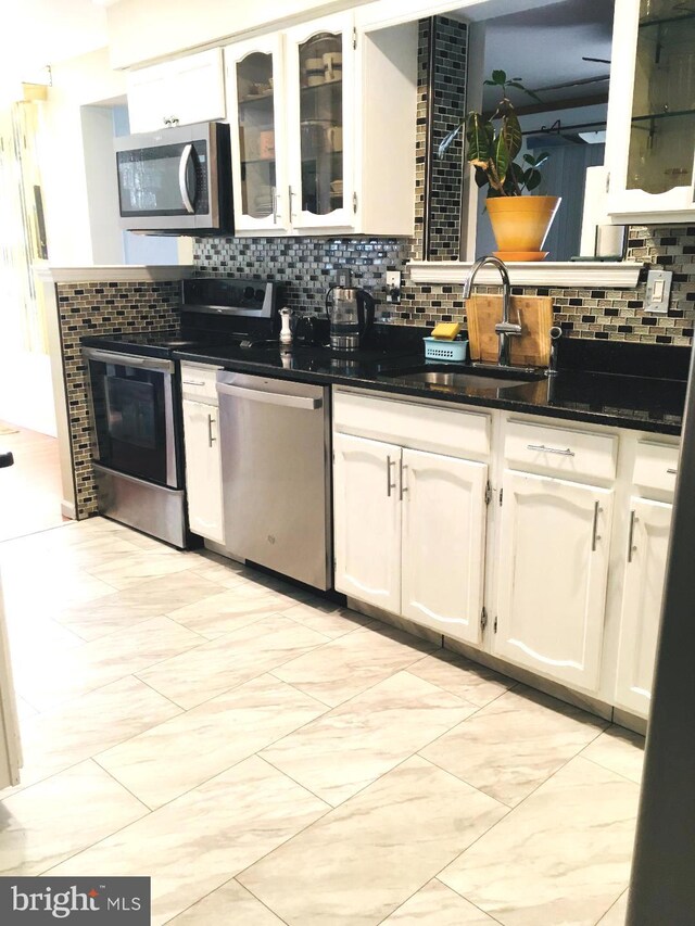 kitchen with stainless steel appliances, sink, decorative backsplash, and white cabinetry