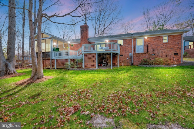 back house at dusk with a deck and a lawn