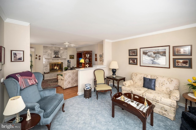 living room featuring ornamental molding, hardwood / wood-style flooring, ceiling fan, and a stone fireplace