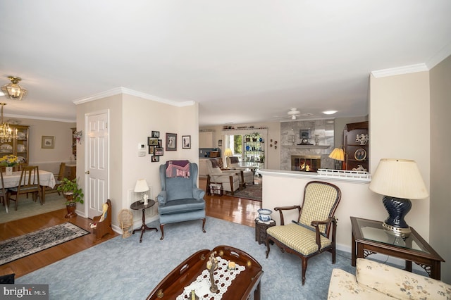 living room featuring ceiling fan with notable chandelier, a fireplace, crown molding, and hardwood / wood-style floors