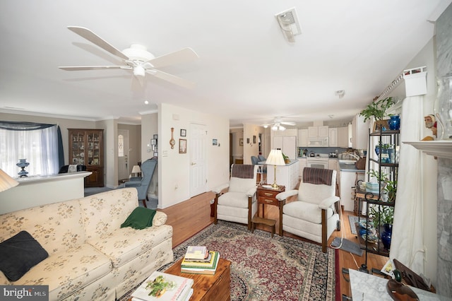 living room with crown molding, hardwood / wood-style floors, and ceiling fan