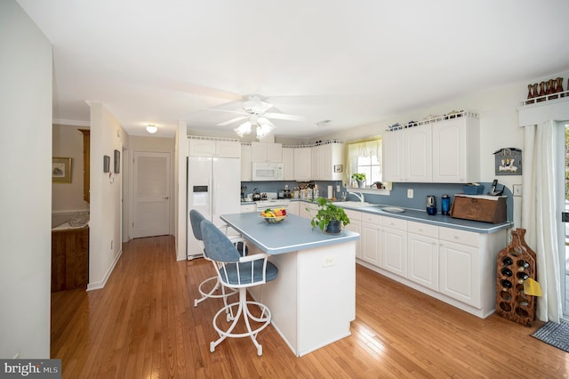 kitchen featuring ceiling fan, a center island, white cabinets, white appliances, and light hardwood / wood-style flooring