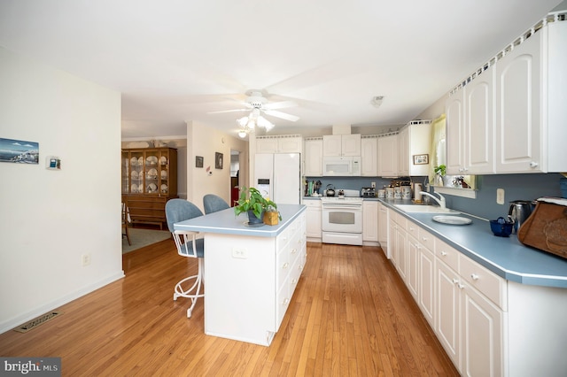 kitchen with a kitchen island, white appliances, sink, light hardwood / wood-style floors, and white cabinetry