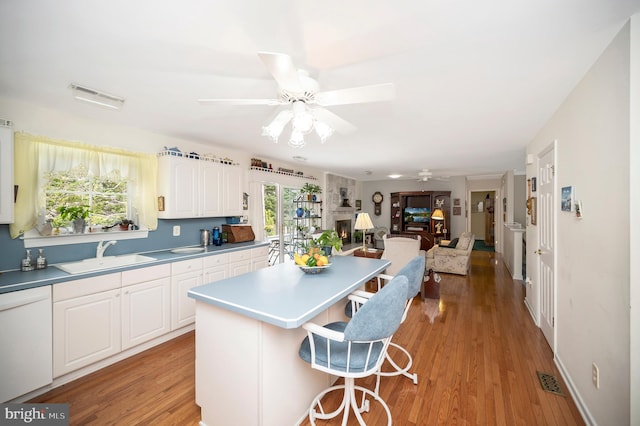 kitchen featuring light hardwood / wood-style floors, white cabinets, sink, and a healthy amount of sunlight