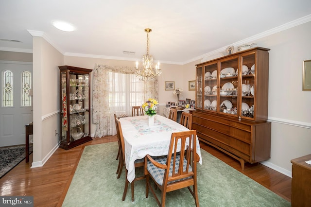 dining space with crown molding, an inviting chandelier, and dark hardwood / wood-style flooring