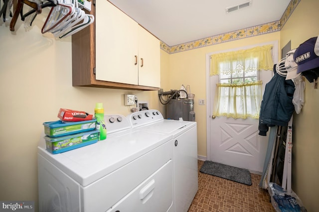 clothes washing area with washing machine and clothes dryer, cabinets, and electric water heater