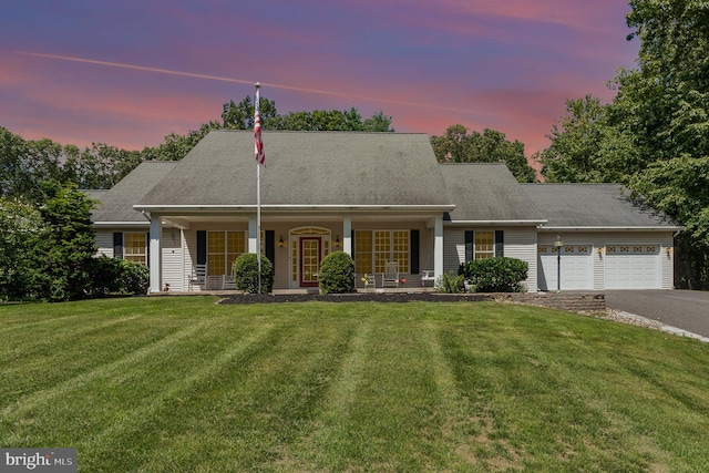 new england style home featuring a lawn, a porch, and a garage