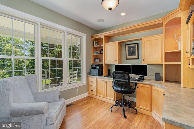 home office with built in desk and light wood-type flooring