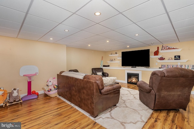 living room with a drop ceiling and wood-type flooring