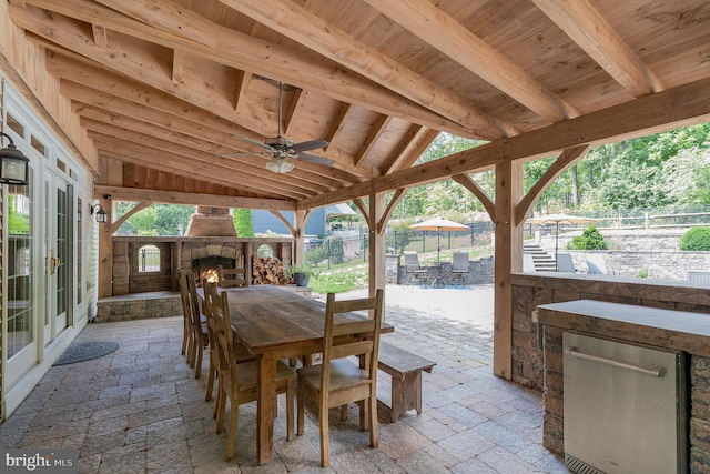 view of patio / terrace featuring ceiling fan, an outdoor stone fireplace, and exterior bar