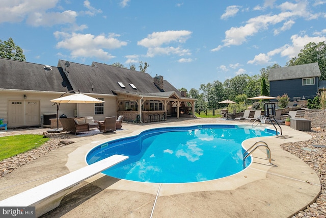 view of swimming pool with a patio, outdoor lounge area, and a diving board