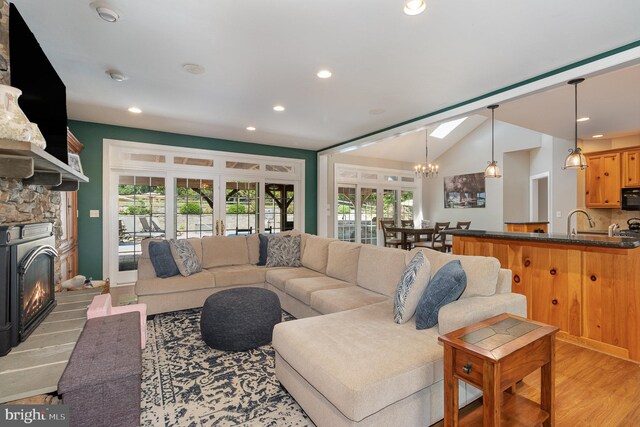 living room featuring a wealth of natural light, a notable chandelier, light wood-type flooring, and lofted ceiling