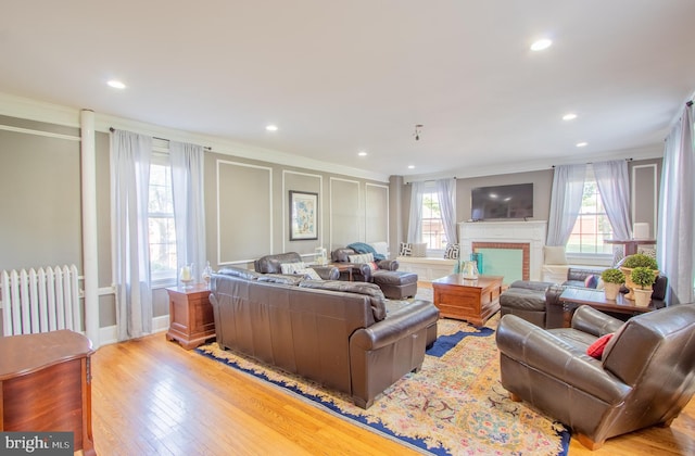 living area with light wood-style flooring, a decorative wall, and crown molding