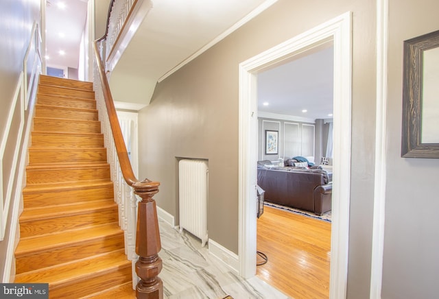 staircase with baseboards, crown molding, and wood finished floors